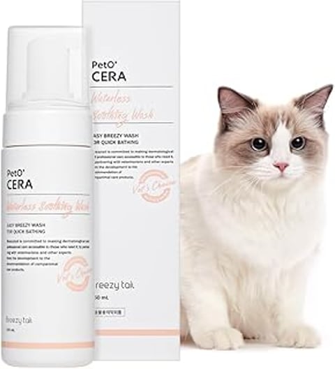 A cat sitting next to a bottle of PetO'Cera waterless shampoo.
