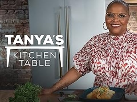 A woman is sitting at a table with a plate of food in front of her.